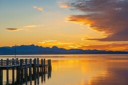 Die Sonne verschwindet über dem Chiemsee hinter den Bergen und tauch die Welt in ein traumhaftes Licht